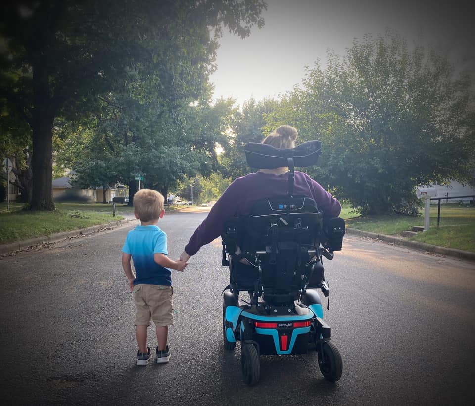 Traci and her grandson out on a walk in summer 2021, the first time she was able to extend her left arm down to hold his hand.